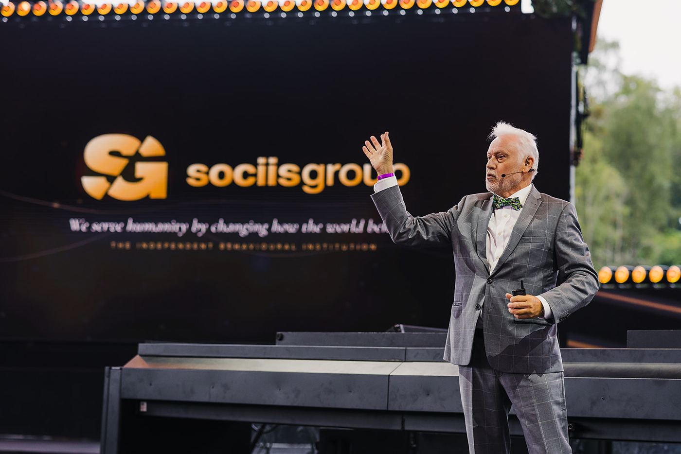 A speaker presenting on stage at The 300, with sociisgroup’s name visible behind him